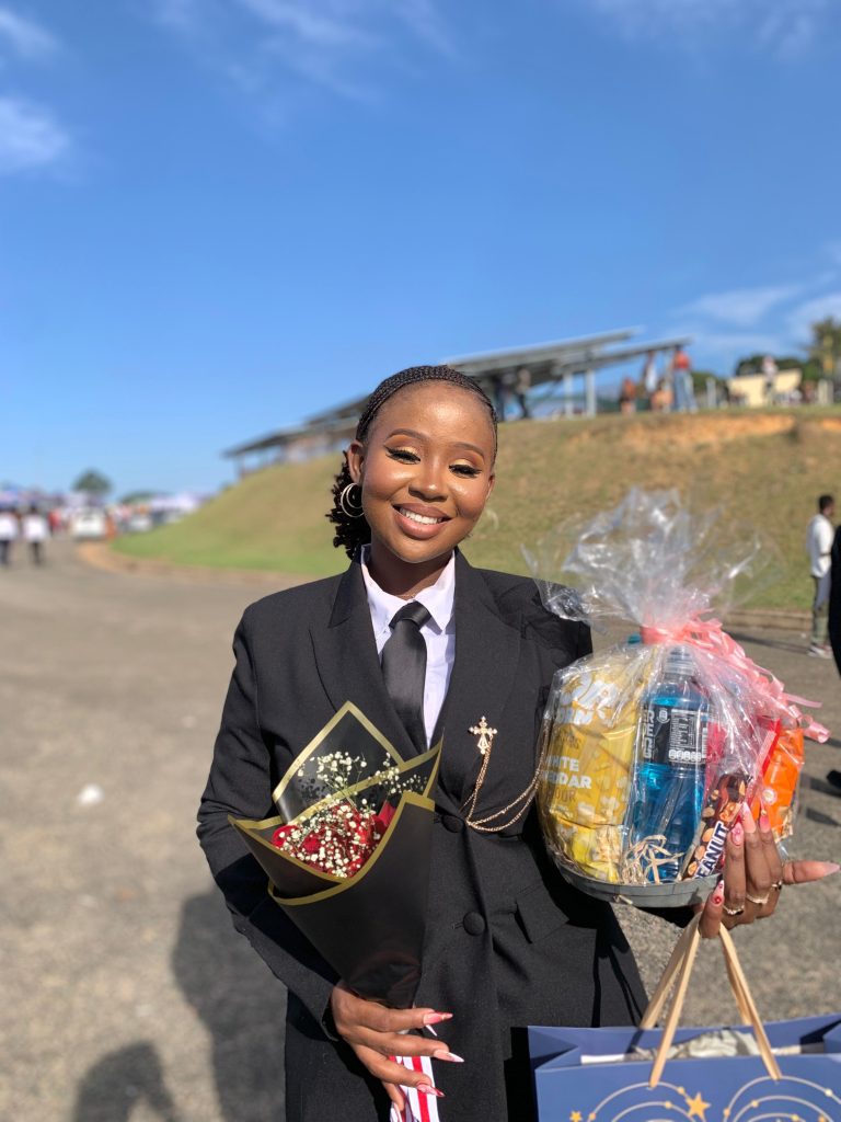 Nokubonga Zwane holding a gift bag and flowers after graduating at the University of Zululand